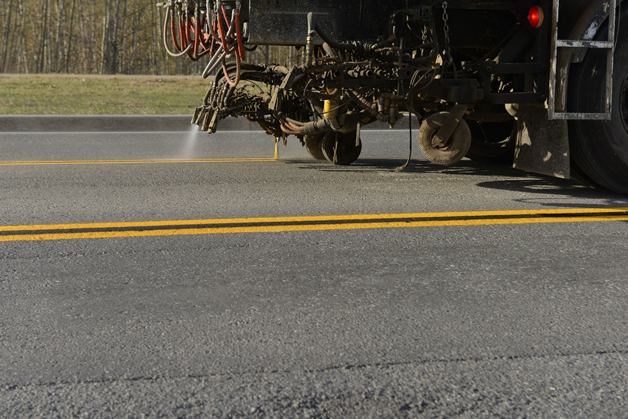 A 773rd Civil Engineering Squadron paint shop striping truck lays down lines on Arctic Warrior Drive while motorists pass on either side. Passing the paint crew is not authorized if they are in the same lane, but in this case the truck is in the turn lane, so motorists should exercise caution when driving by. (U.S. Air Force photo by Airman 1st Class Kyle Johnson)