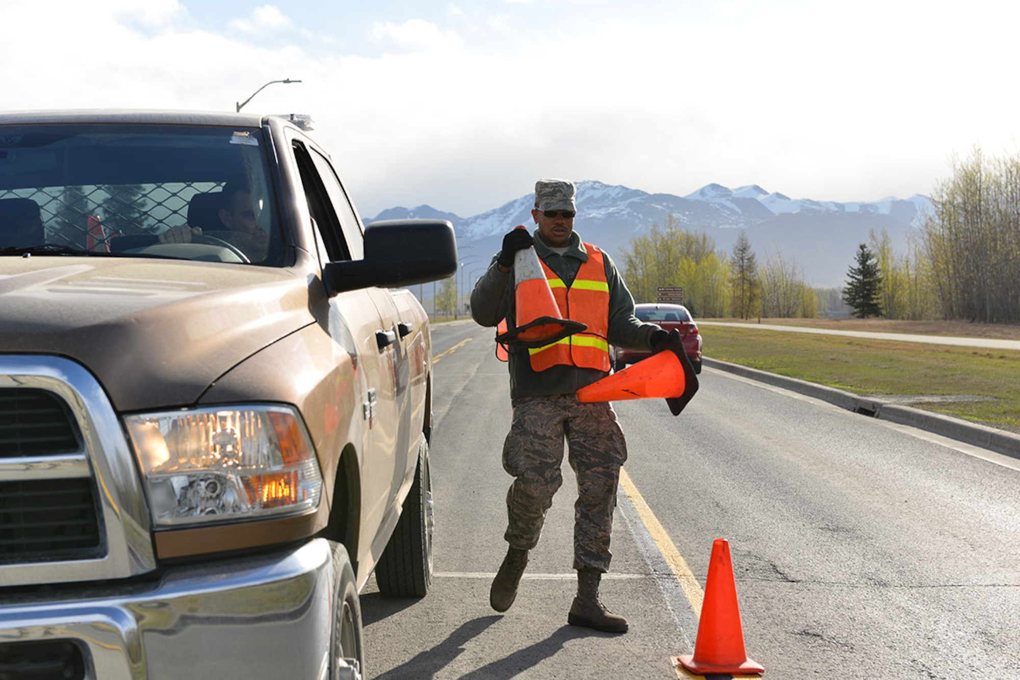 Airman 1st Class Nicholas McGee, a 773rd Civil Engineering Squadron structural apprentice augmenting the paint shop walks behind a striping truck, placing cones to show motorists where paint is wet. When driving near or by a paint team, motorists should exercise caution so as to not damage their vehicles or place the Airmen at risk. (U.S. Air Force photo by Airman 1st Class Kyle Johnson)