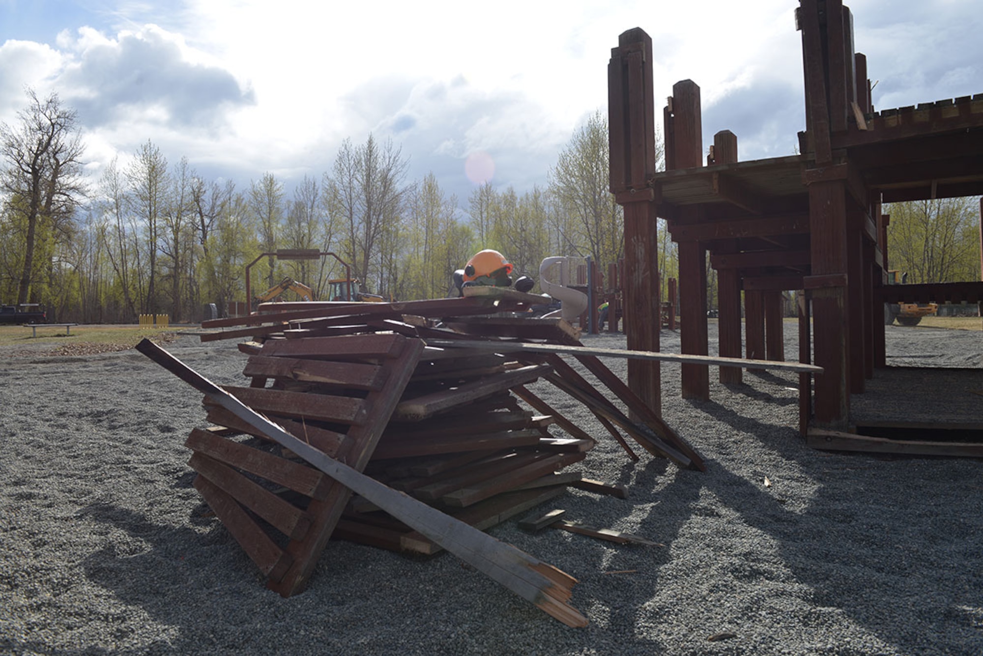 A wood pile rests where a play structure once stood as 773d Civil Engineer Squadron personnel work to demolish the Cottonwood Park playground on Joint Base Elmendorf-Richardson, Alaska, April 26, 2016. Replacement play structures are military- and Alaska-inspired, and will provide learning opportunities for children, said Tech. Sgt. Jeremy Faulkner, 673d CES project inspector. (U.S. Air Force photo by Airman 1st Class Javier Alvarez)