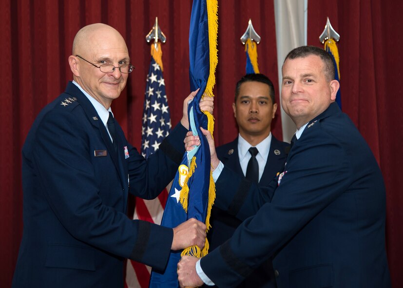Lt. Gen. Arnold W. Bunch, Jr., military deputy, Office of the Assistant Secretary of the Air Force for Acquisition, passes the Air Force flag to Maj. Gen. Dwyer L. Dennis during the Command, Control, Communications, Intelligence and Networks change in leadership at the Minuteman Commons April 25, while Master Sgt. Siam Bean looks on. As program executive officer for C3I and Networks, Dennis is responsible for more than 2,200 personnel and acquisition execution of a $10.9 billion portfolio developing, deploying and sustaining Air Force, joint and coalition cyberspace, networks, cryptologic and data link systems to enable decisive combat operations. (U.S. Air Force photo by Mark Herlihy)