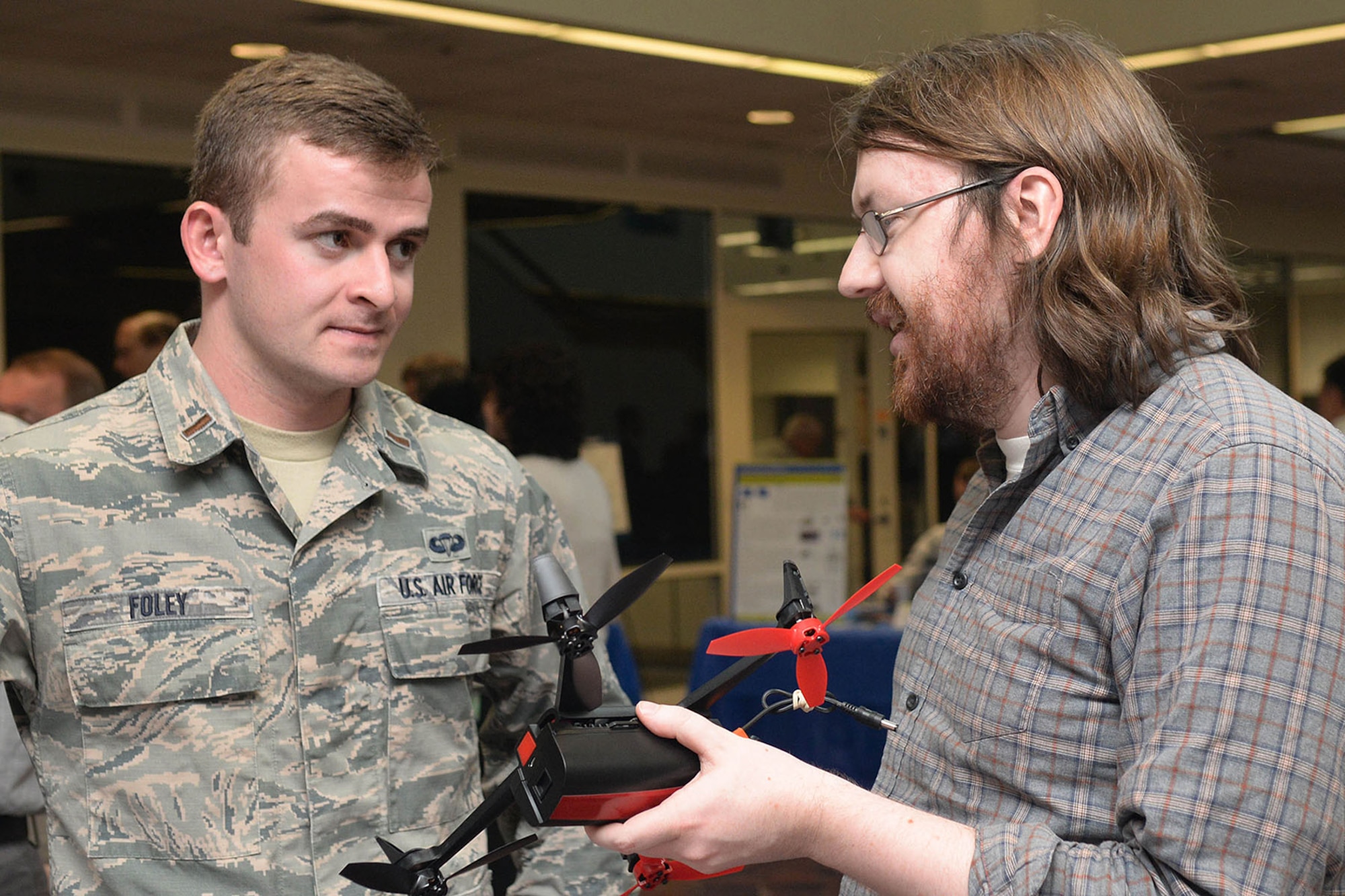 Second Lt. Michael Foley, Engineering and Technical Management executive officer, speaks to Neal Humphrey, MITRE communications engineer and principal
investigator, about robust communications protocols for airborne multi-agent robotic
systems of unmanned aerial vehicles during an Innovation Exchange April 26 in the Building 1612 atrium at Hanscom Air Force Base, Mass. The exchange was hosted by Hanscom's Engineering and Technical Management Directorate in conjunction with The
MITRE Corp. and offered an opportunity for information sharing in the areas
of cybersecurity, communications and networking, and the future of command
and control. (U.S. Air Force photo by Linda LaBonte Britt)
