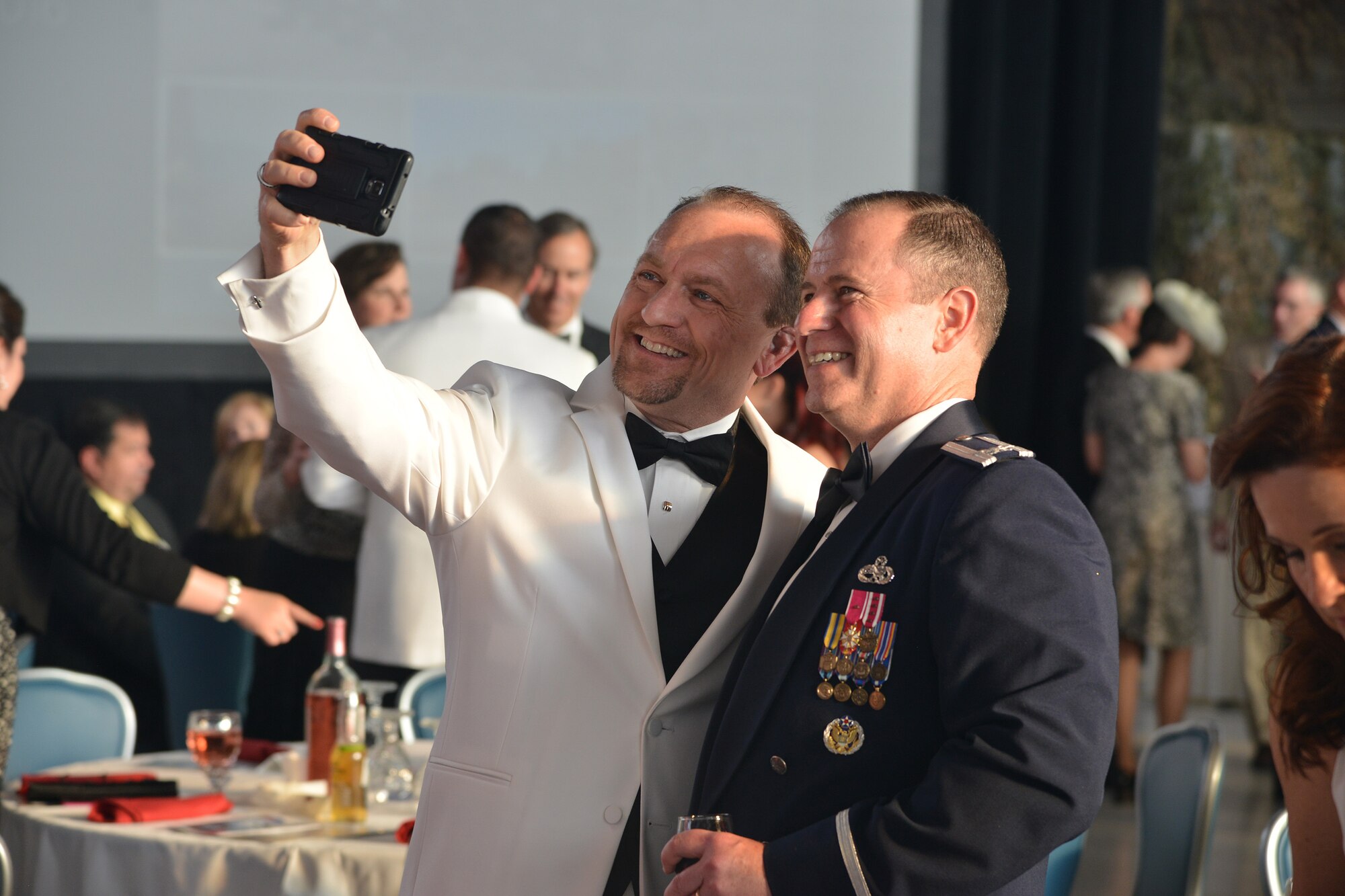 Col. Eric Froehlich, left, commander of the 377th Air Base Wing, takes a moment at Kirtland's anniversary banquet to take a selfie with Mayor Gregory Hull, mayor of Rio Rancho. About 500 people attended the anniversary banquet at the New Mexico Air National Guard’s 150th Special Operations Wing hangar April 16. The banquet had a 1940s theme, to remember the opening of Albuquerque Army Air Base on Jan. 7, 1941. Period attire and static displays of World War II vehicles helped bring the theme to life. (Photo by Todd Berenger)