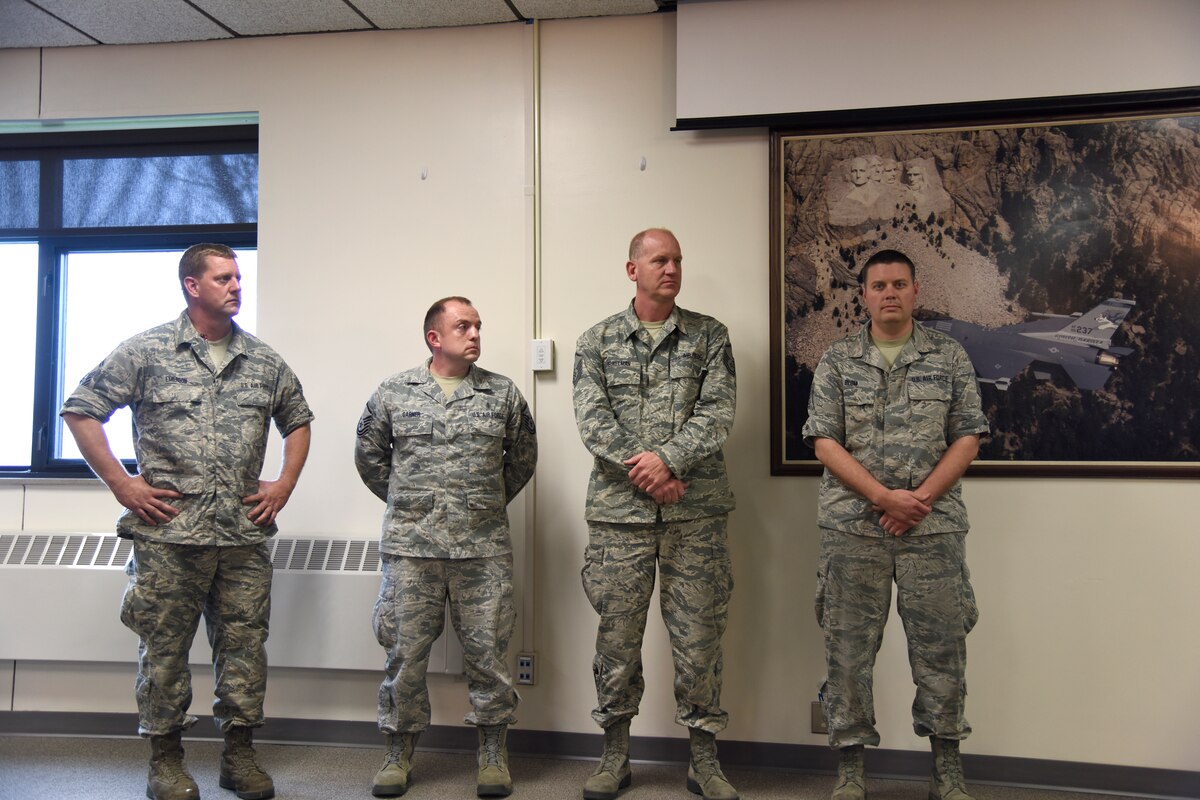 SIOUX FALLS, S.D. - Pictured left to right, Senior Master Sgt. Shawn Emerson, Master Sgt. Brent Garner, Master Sgt. Paul Beukelman, and Tech. Sgt. Nate Blom, all full-time employees of the South Dakota Air National Guard, listen as Col. Nate Alholinna, 114th Fighter Wing vice commander, reads a letter from Lutheran Social Services commending the Airmen for the time they spent as mentors over the past year. Master Sgt. Casey Bullis is also a mentor under this program but was not available for the photograph.(U.S. National Guard photo by Senior Master Sgt. Nancy Ausland)