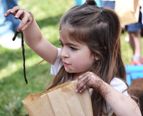 Madie Janaros puts a worm in her take home bag during the annual Earth Day event at Schriever Air Force Base, Colorado, Friday, April 22, 2016. Attendees were encouraged to take home the worms they dug out of a plastic pool filled with dirt in order to help fertilize their home gardens. (U.S. Air Force photo/Brian Hagberg)