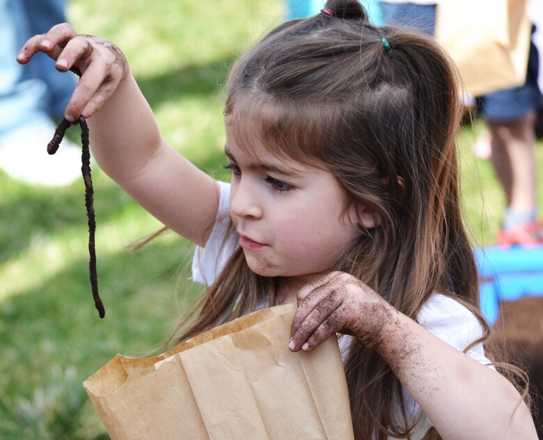 Madie Janaros puts a worm in her take home bag during the annual Earth Day event at Schriever Air Force Base, Colorado, Friday, April 22, 2016. Attendees were encouraged to take home the worms they dug out of a plastic pool filled with dirt in order to help fertilize their home gardens. (U.S. Air Force photo/Brian Hagberg)