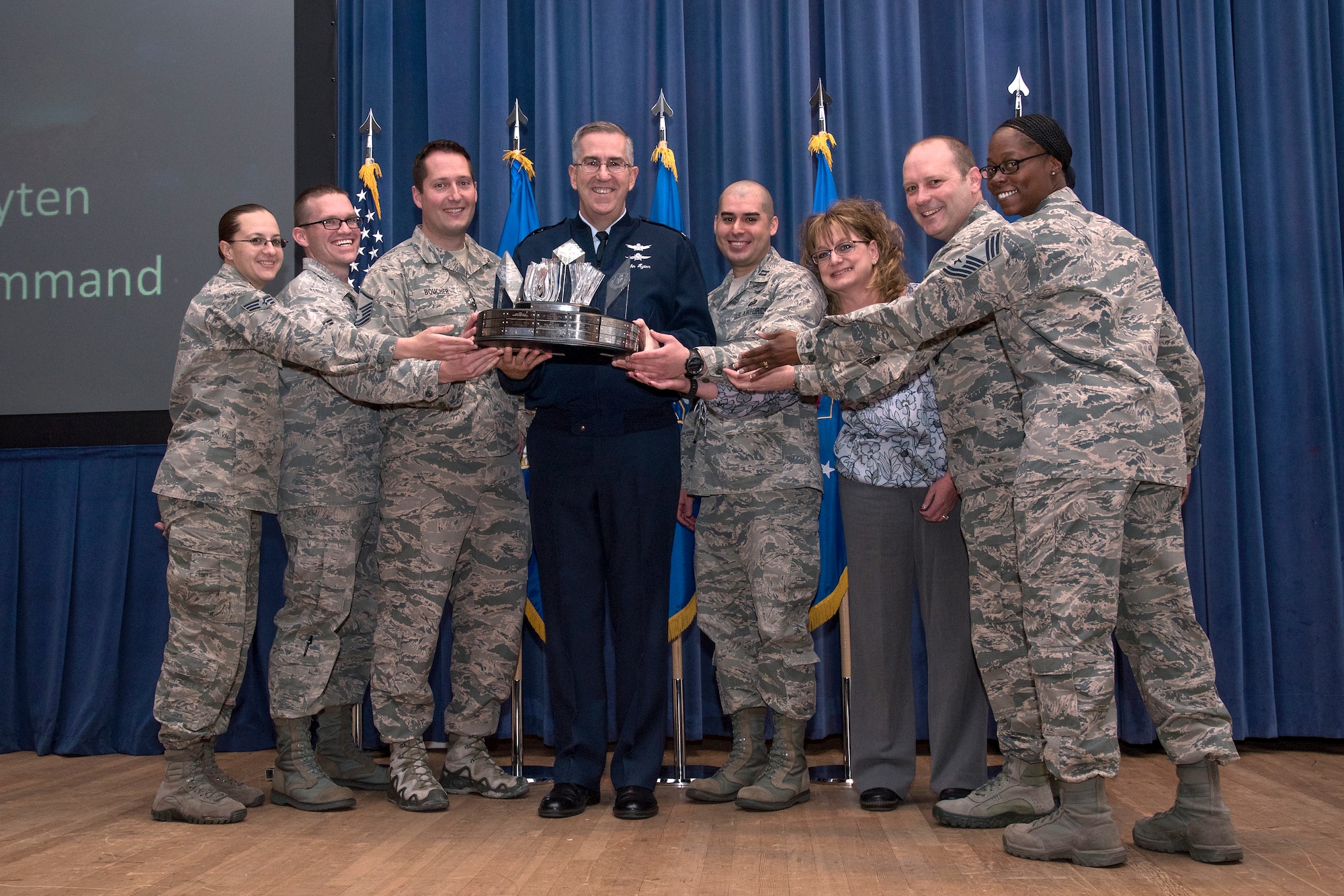 PETERSON AIR FORCE BASE, Colo. – Gen. John E. Hyten, Air Force Space Command commander presents the General Thomas S. Moorman Jr. Trophy to the 21st Space Wing for best overall wing in Air Force Space Command on April 21, 2016 during the 21st Space Wing Commander’s Call.  Accepting the trophy (from left) Senior Airman Megan Karlsen, 21st Security Forces Squadron, Staff Sgt. Josh Heroux, 21st Medical Group, Master Sgt. Chad Boucher, 721st Security Forces Squadron, Capt. Cesar Carvajal, 21st Operations Group, Carrie Granzella, 21st Comptroller Squadron, Col. Douglas Schiess, 21st Space Wing commander and Chief Master Sgt. Nanette Klingaman, 721st Mission Support Group superintendent. (U.S. Air Force Photo by Craig Denton)

