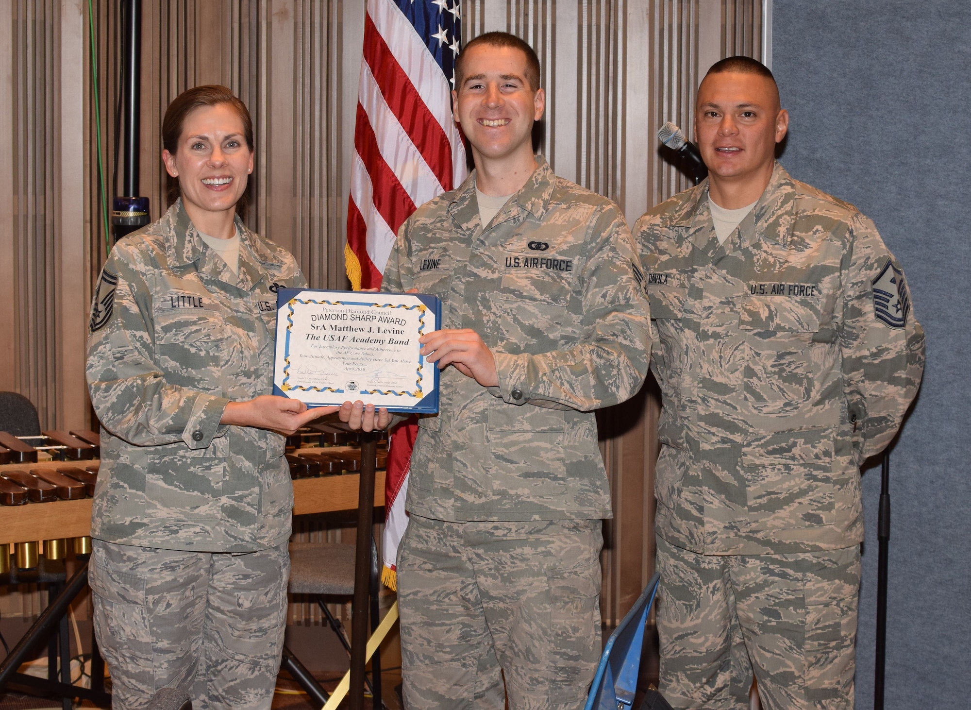PETERSON AIR FORCE BASE, Colo. – Senior Airman Matthew Levine, U.S. Air Force Academy Band, is presented the April Diamond Sharp Award by Senior Master Sgt. Noelle Little, USAF Academy Band first sergeant and Master Sgt. Roger Davila, 561st Network Operations Center first sergeant. The Diamond Sharp award is presented by the Peterson Diamond Council and recognizes superior performers. (Courtesy Photo)