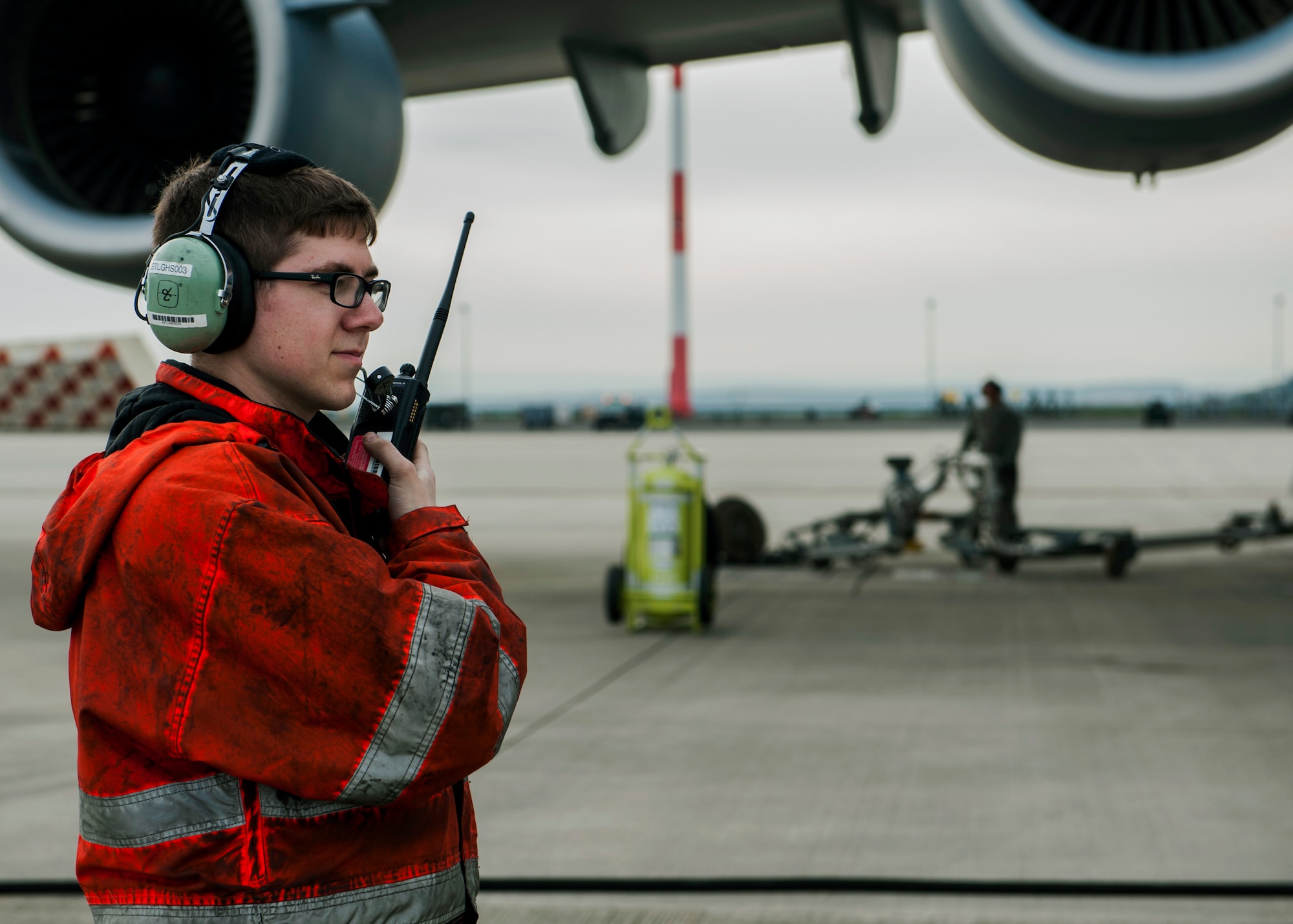 U.S. Air Force Senior Airman Hunter Stewart, a 726th Air Mobility Squadron instruments and flight control journeyman, talks into a two-way radio during a Boeing C-17 Globemaster III refuel on the flightline at Spangdahlem Air Base, Germany, April 22, 2016. The squadron emphasizes safe and secure communication to ensure aircraft can effectively carry out their mission. (U.S. Air Force photo by Airman 1st Class Timothy Kim/Released)