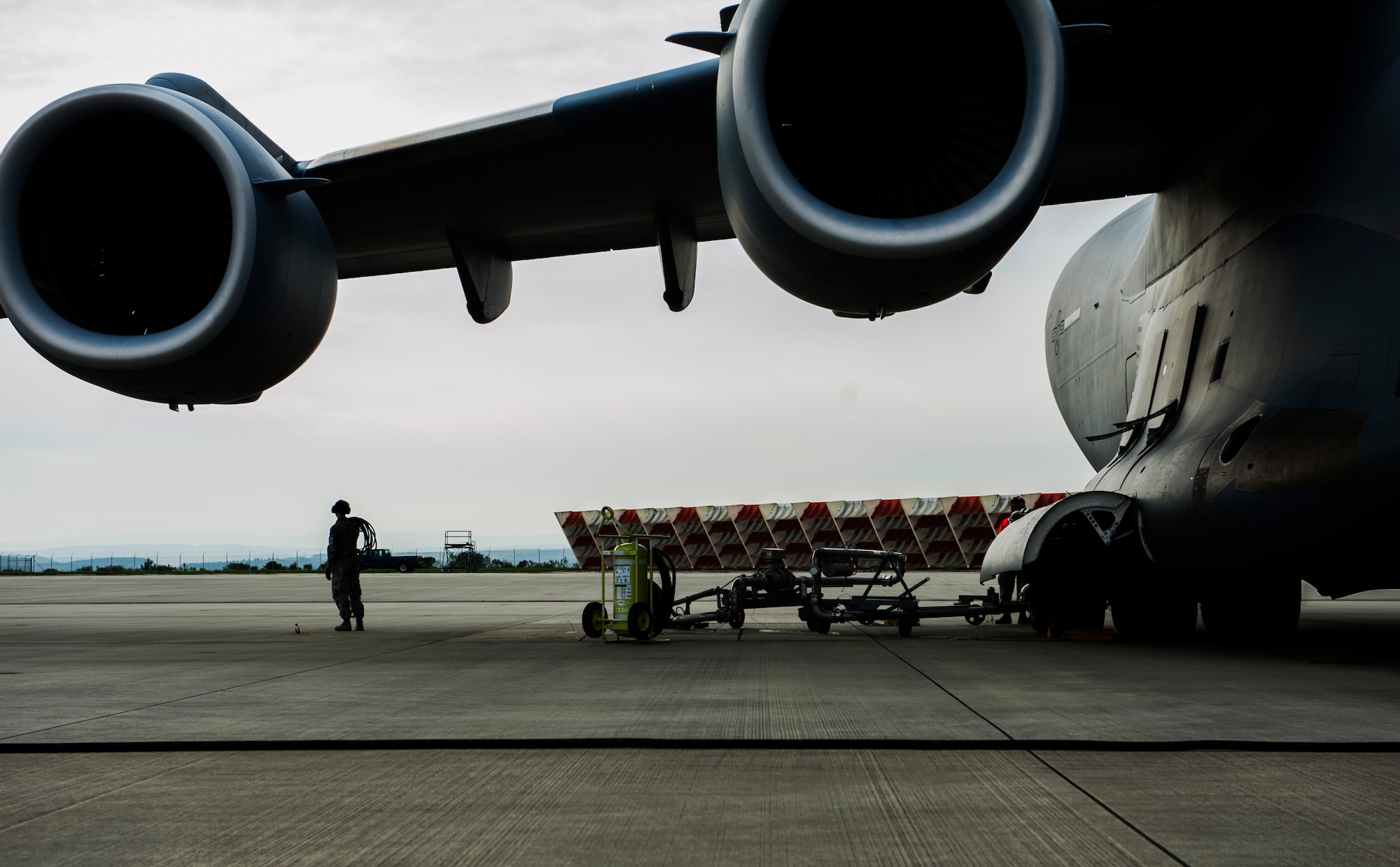 An Airman assigned to the 726th Air Mobility Squadron coils a chord during a Boeing C-17 Globemaster III refuel on the flightline at Spangdahlem Air Base, Germany, April 22, 2016. The squadron supports passing heavy cargo aircraft through refueling, cargo and crew maintenance and other necessities required for mission success. (U.S. Air Force photo by Airman 1st Class Timothy Kim/Released)