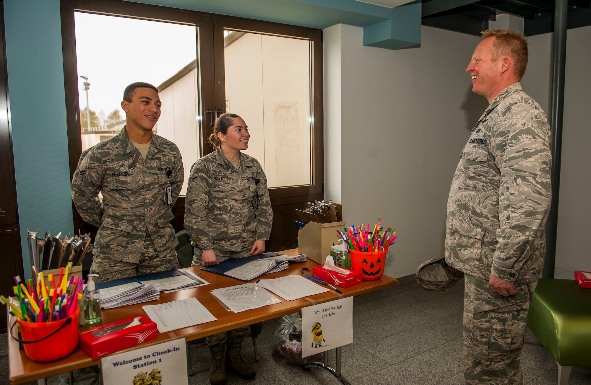 U.S. Air Force Col. Joe McFall, 52nd Fighter Wing commander, right, speaks with U.S. Air Force Airman 1st Class Malik Veveiros, left, and U.S. Air Force Airman Davina Fausto, both 52nd Dental Squadron dental assistants, during the dental clinic’s semi-annual children’s walk-in at Spangdahlem Air Base, Germany, April 22, 2016. The dental clinic processed children from all age groups to ensure 52nd Fighter Wing family members were received proper the dental care. (U.S. Air Force photo by Airman 1st Class Timothy Kim/Released)