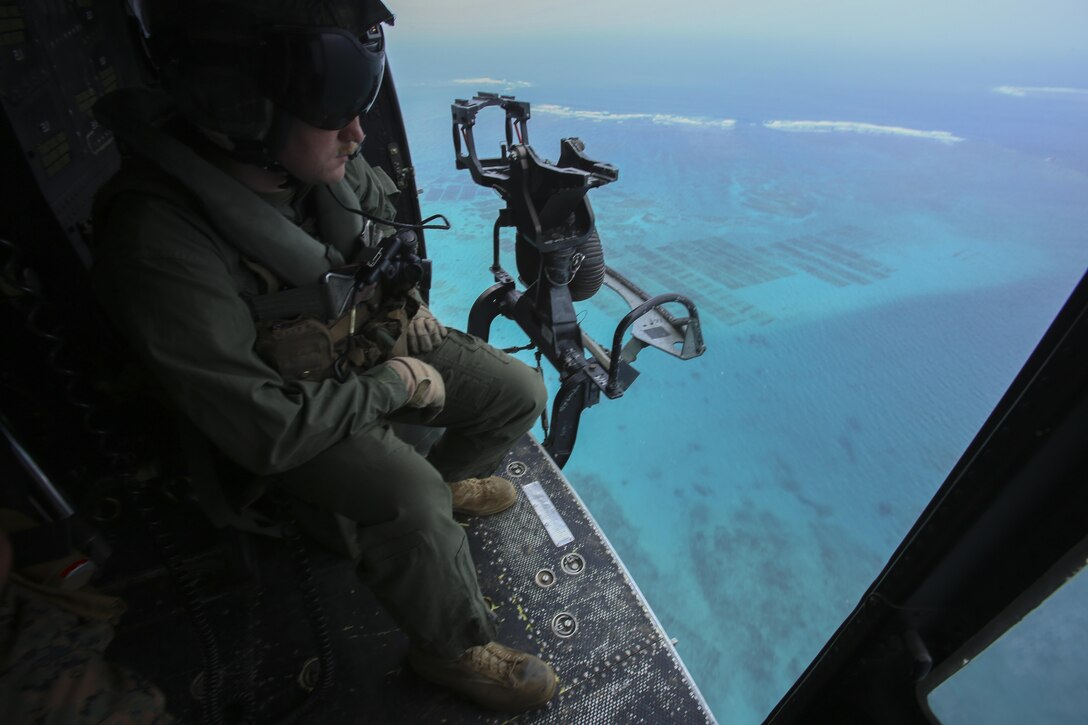 Sgt. Jeffrey L. Allen scopes out the terrain from his seat in a UH-1Y Huey, April 8, 2016, at Marine Corps Air Station Futenma, Okinawa, Japan. Allen, along with other crew chiefs and aircraft maintainers, may work up to 16 hours a day performing maintenance and checks on aircraft to ensure safe missions. Allen, from Ennis, Texas, is with Marine Light Attack Helicopter Squadron 167, currently supporting Marine Aircraft Group 36, 1st Marine Aircraft Wing, III Marine Expeditionary Force, under the unit deployment program. 