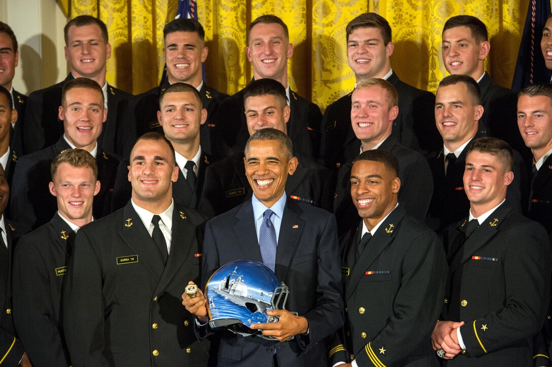 President Barack Obama holds a Navy football helmet and ring while posing for a photo with the football team from the U.S. Naval Academy after he awarded the Commander in Chief's Trophy to the team at the White House in Washington, D.C., April 27, 2016. DoD photo by EJ Hersom