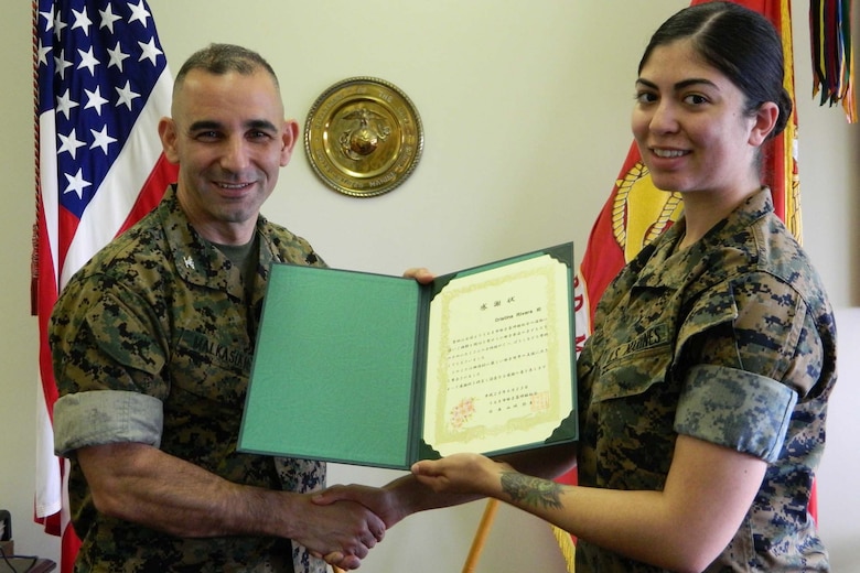 Col. George G. Malkasian, Camp Courtney commanding officer, thanks Cpl. Cristina Rivera for the contribution to build friendship with local community and handed her the letter of appreciation. 