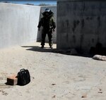Staff Sgt. John Nelson, 512th Explosive Ordnance Flight, simulates inspecting a suspected improvised explosive device inside a computer bag during a training exercise April 3, 2016 at Dover Air Force Base, Delaware. Nelson was joined by his flight's program manager who evaluated his performance. (U.S. Air Force photo/Staff Sgt. Joe Yanik)