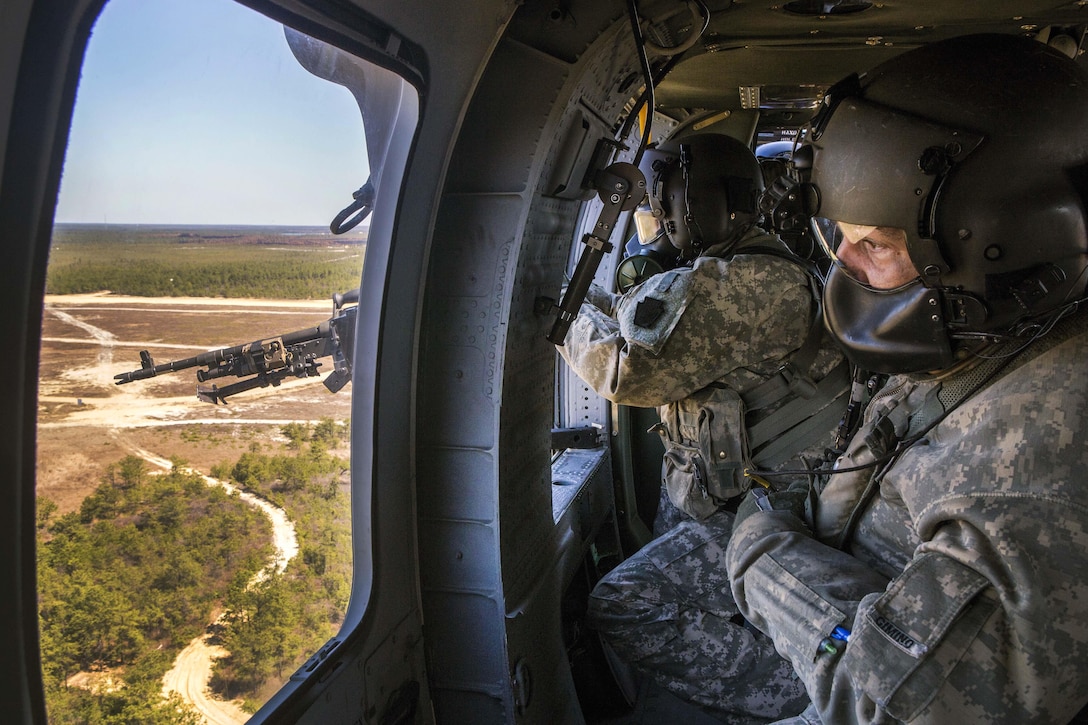 Army Staff Sgt. Paul Cimino, right, observes Army Sgt. William Harpe firing at targets with an M240B machine gun during an aerial gunnery training exercise over Warren Grove Gunnery Range, N.J., April 15, 2016. Cimino is master gunner and Harpe is a crew chief assigned to the New Jersey Army National Guard’s 150th Assault Helicopter Battalion. Air National Guard photo by Master Sgt. Mark C. Olsen