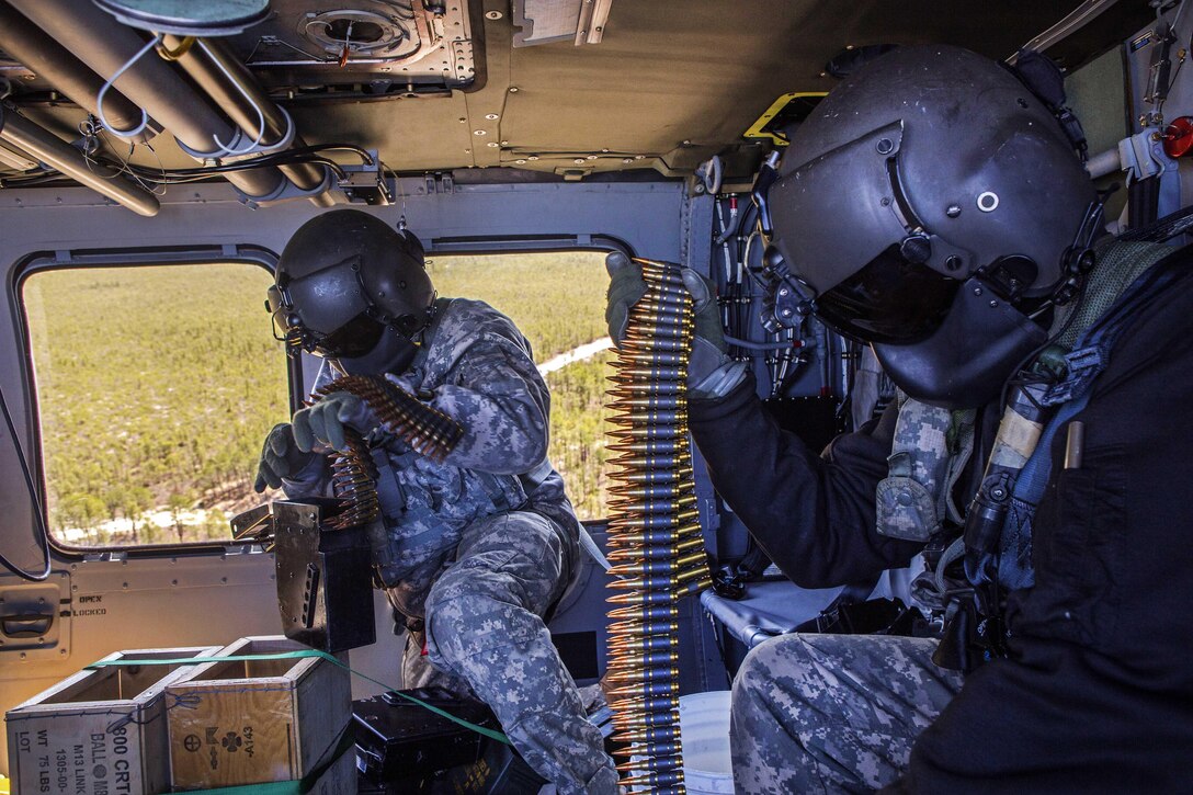 Army crew chiefs reload canisters with ammunition inside a UH-60 Black Hawk helicopter during an aerial gunnery training exercise over Warren Grove Gunnery Range, N.J., April 15, 2016. Air National Guard photo by Master Sgt. Mark C. Olsen