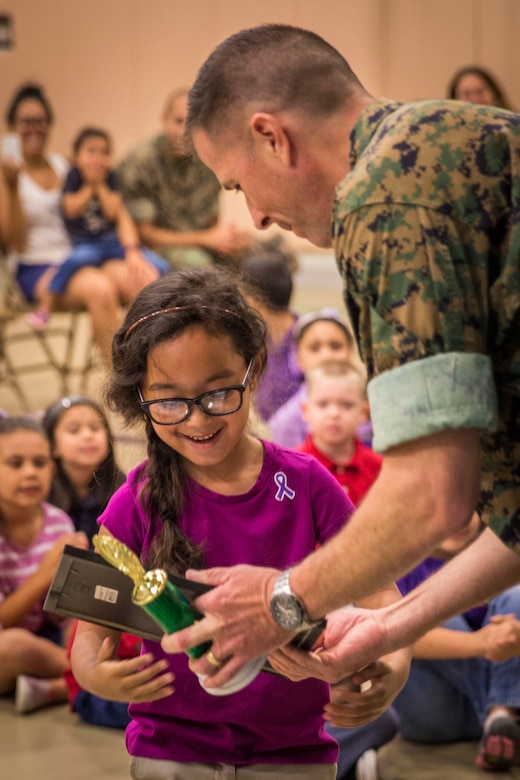 Lt. Col Sean Henrickson presents a student with an award during an Earth Day assembly at Middleton S. Elliott Elementary School aboard Laurel Bay April 22. Students drew Earth Day related artwork for a competition judged by the recycling department aboard Marine Corps Air Station Beaufort. Henrickson is the executive officer of MCAS Beaufort. 