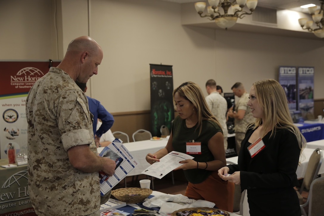 Master Gunnery Sgt. Steve Lowe, senior enlisted advisor, Marine Corps Tactics and Operations Group, speaks with Sharon Guervara, government sales manager, and Haley Scott, government contract manager, Divine Imaging Inc., about the different products and services the company offers at the Officers’ Club during the Tactical and Technology Day Expo April 19, 2016. (Official Marine Corps photo by Pfc. Dave Flores/Released)