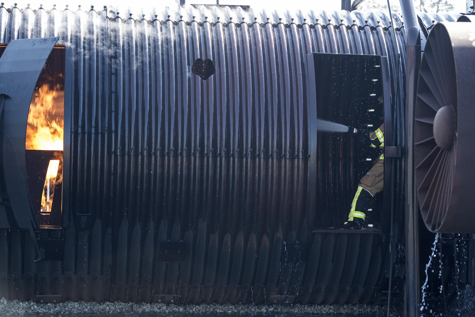 A firefighter douses a fire with water during aircraft live fire training, April 27, 2016, at Moody Air Force Base, Ga. In addition to combatting fires outside the prop aircraft, firefighters had to enter and combat the fires inside. (U.S. Air Force photo by Airman 1st Class Janiqua P. Robinson/Released)