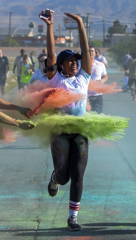 An Airman gets two different colors of chalk thrown on her during the 5K Color Run/Walk to raise awareness for April campaigns at Nellis Air Force Base, Nev., April 22, 2016. The green and red chalk thrown during the color run represent the Chapel and Mental Health. (U.S. Air Force photo by Airman 1st Class Kevin Tanenbaum)