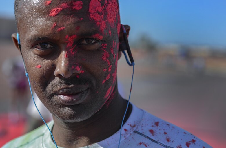 An Airman poses for a portrait after having red chalk thrown on him during the 5K Color Run/Walk to raise awareness for April campaigns at Nellis Air Force Base, Nev., April 22, 2016. Airmen and families were encouraged to come out in support of the numerous campaigns taking place during April. (U.S. Air Force photo by Airman 1st Class Kevin Tanenbaum)