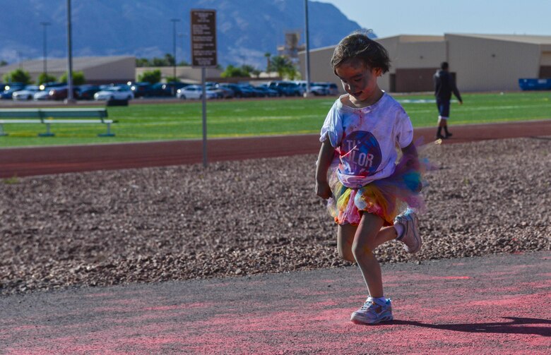 A child races towards the finish line during the 5K Color Run/Walk at Nellis Air Force Base, Nev., April 22, 2016. All DoD ID cardholders and their families were welcomed to participate in the event. (U.S. Air Force photo by Airman 1st Class Nathan Byrnes)