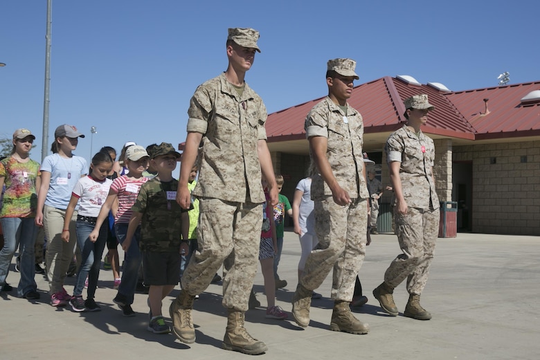 Marine Corps Communication-Electronics School Marines lead Combat Center children in marching and drill movements during the beginning of the Lifestyle, Insights, Networking, Knowledge, and Skills annual Combined Arms Exercise for Kids at Felix Field April 20, 2016. (Official Marine Corps photo by Cpl. Thomas Mudd/Released)