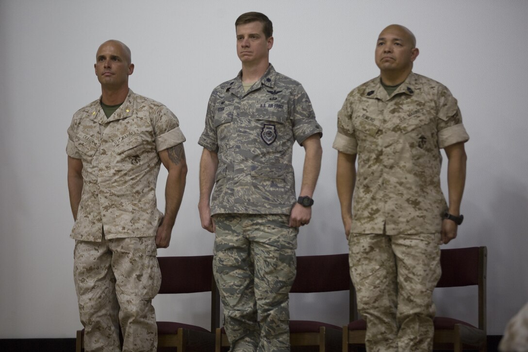 U.S. Marine Corps Maj. Chad E. Craven, commanding officer, Delta Company, Communication Training Battalion, U.S. Air Force Lt. Col.  Russell “Bones” Cook, squadron commander, 563 Operations Support Squadron, and Master Gunnery Sgt. Jerry Romero, senior enlisted advisor, Company D, CTB, stand at the position of attention during the playing of the national anthem during Craven’s retirement ceremony at the base theater April 20, 2016. Craven retired after 24-years of honorable service. (Official Marine Corps photo by Cpl. Julio McGraw/Released)