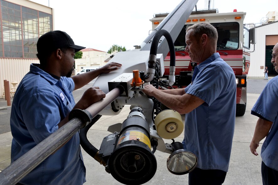 Keith Widemon, left, and Tim Stotenburg, right, both from the 60th Logistics Readiness Squadron, inspect a hose on fire truck April 26, at Travis Air Force Base, California. The 60th LRS Vehicle Management Flight is responsible for the servicing, repair and maintenance of nearly every general purpose vehicle assigned to the installation. (U.S. Air Force photo by Staff Sgt. Charles Rivezzo)  