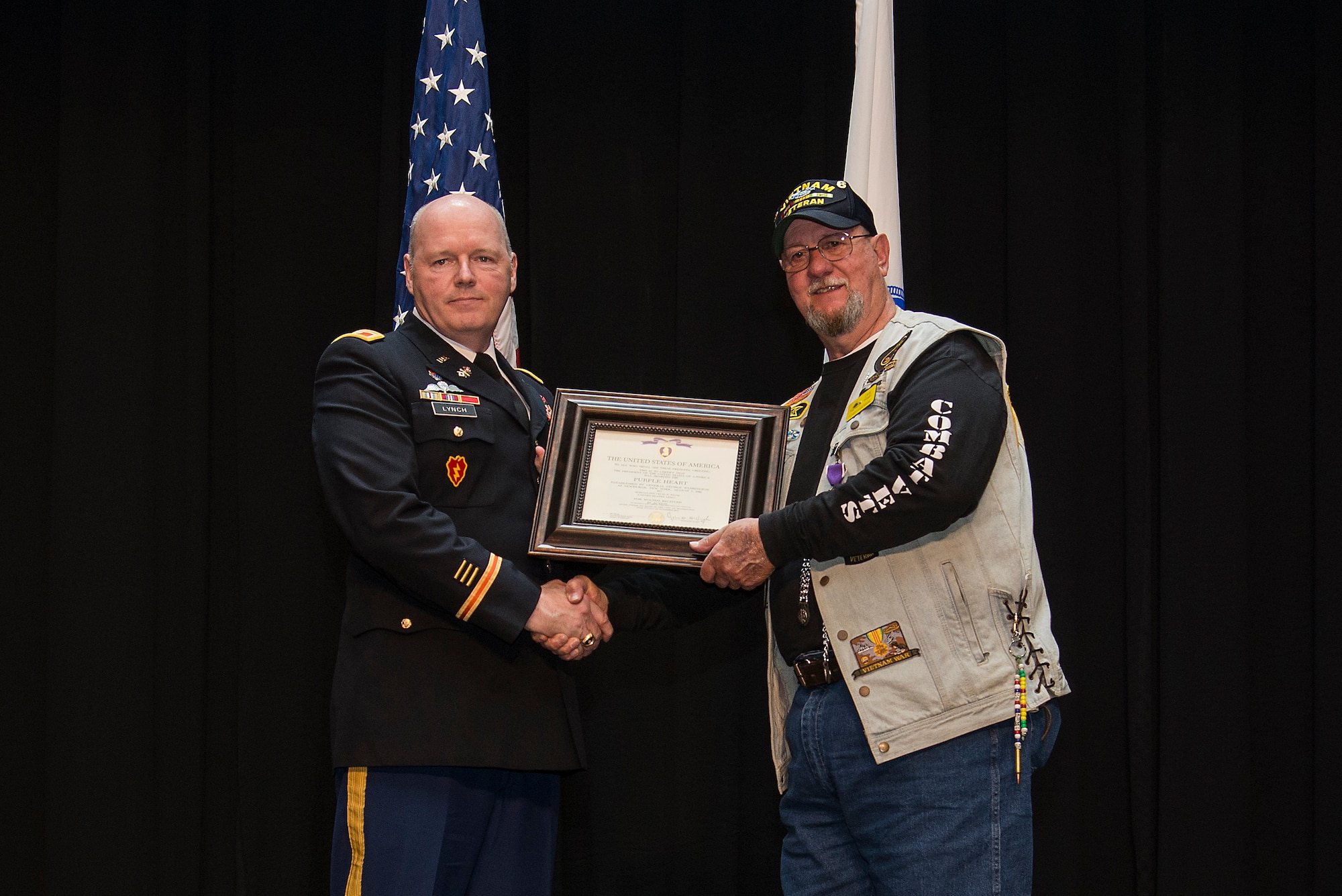 Army Col. Kevin Lynch presents Cecil Wade with a Purple Heart Medal, April 22, 2016 at Scott Air Force Base, Illinois, for injuries he received during Vietnam War. Wade was injured in Vietnam after jumping out of a helicopter he was forced to evacuate. He landed on one side and injured one of his legs critically. (Air Force photo by Airman 1st Class Gwendalyn Smith)