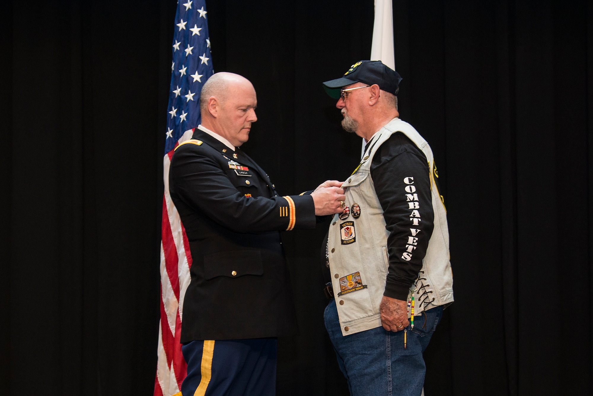 Army Col. Kevin Lynch presents Cecil Wade with a Purple Heart Medal, April 22, 2016 at Scott Air Force Base, Illinois, for injuries he received during Vietnam War. Wade was injured in Vietnam after jumping out of a helicopter he was forced to evacuate. He landed on one side and injured one of his legs critically. (Air Force photo by Airman 1st Class Gwendalyn Smith)