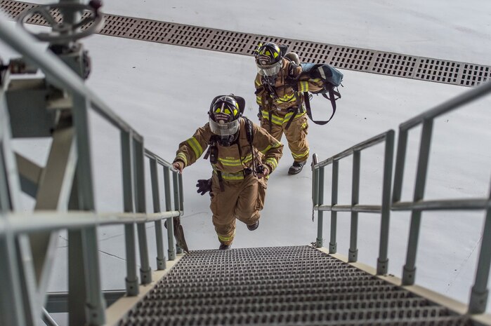 Airmen from the 628th Civil Engineer Squadron fire emergency services flight head up steps during a confined space emergency extraction exercise, April 22, 2016, at Joint Base Charleston, S.C. The exercise simulated a person losing consciousness inside one of the four fuel tanks aboard a C-17 Globemaster III. (U.S. Air Force photo/Staff Sgt. Jared Trimarchi) 