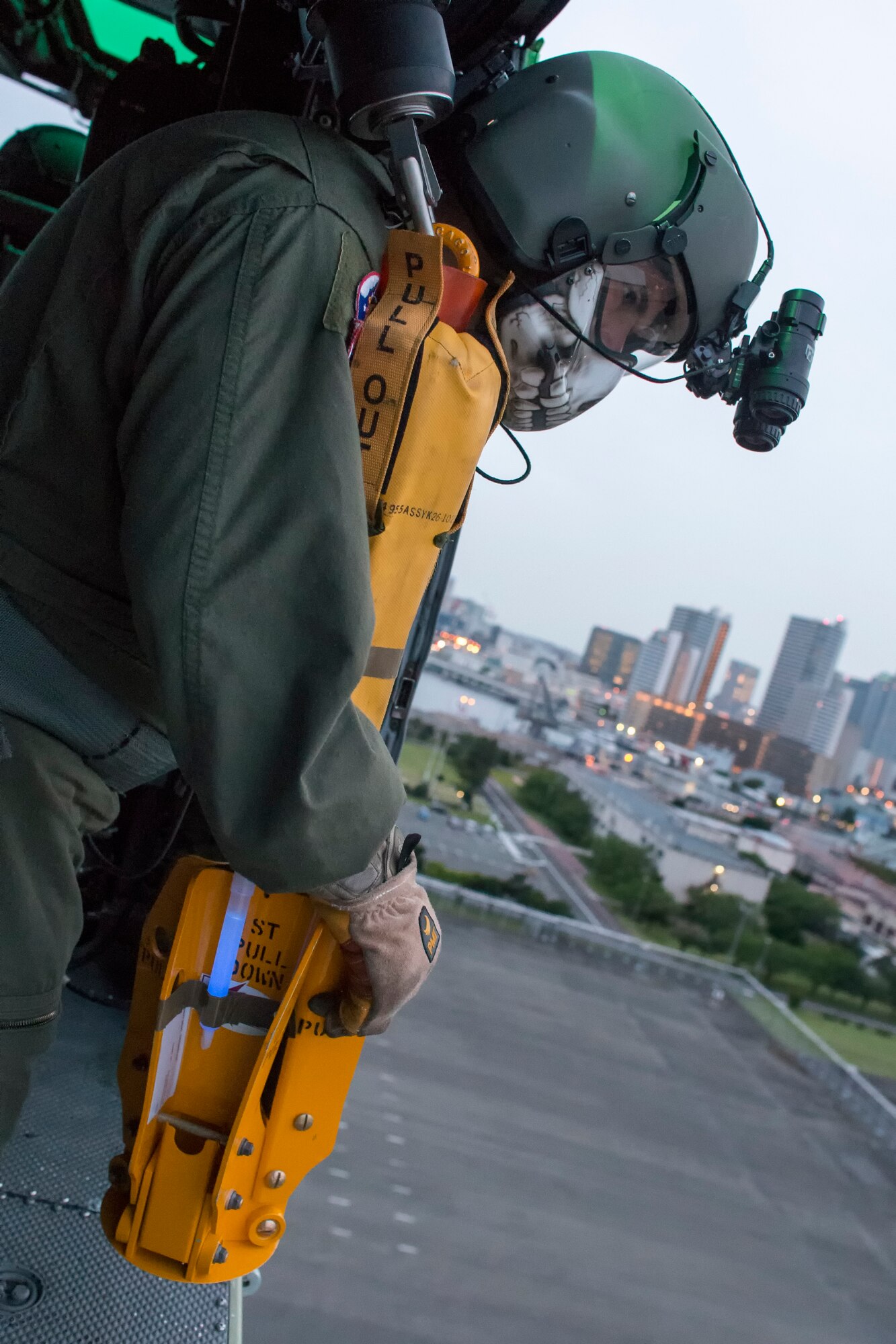 Tech. Sgt. Christopher Rector, 459th Airlift Squadron UH-1N Iroquois special missions aviator evaluator, prepares to lower a hoist during a training flight over U.S. Army Garrison Yokohama North Dock, April 25, 2016. The 459 AS regularly conducts training missions to remain proficient with necessary skills to support any contingency. (U.S. Air Force photo by Yasuo Osakabe/Released)