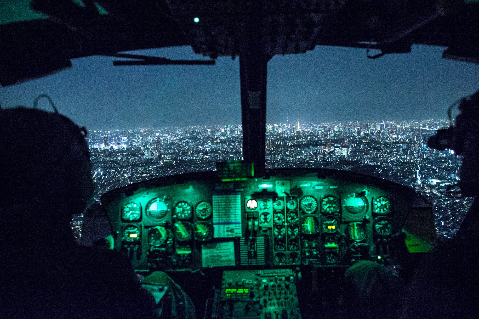 (Right to left) Capt. Jonathan Bonilla, and 1st Lt. Vicente Vasquez, both with the 459th Airlift Squadron UH-1N Iroquois pilots, fly over Tokyo after completing night training, April 25, 2016. The 459 AS frequently trains on a multitude of scenarios in order to stay prepared for potential real-world contingencies and operations. (U.S. Air Force photo by Yasuo Osakabe/Released)