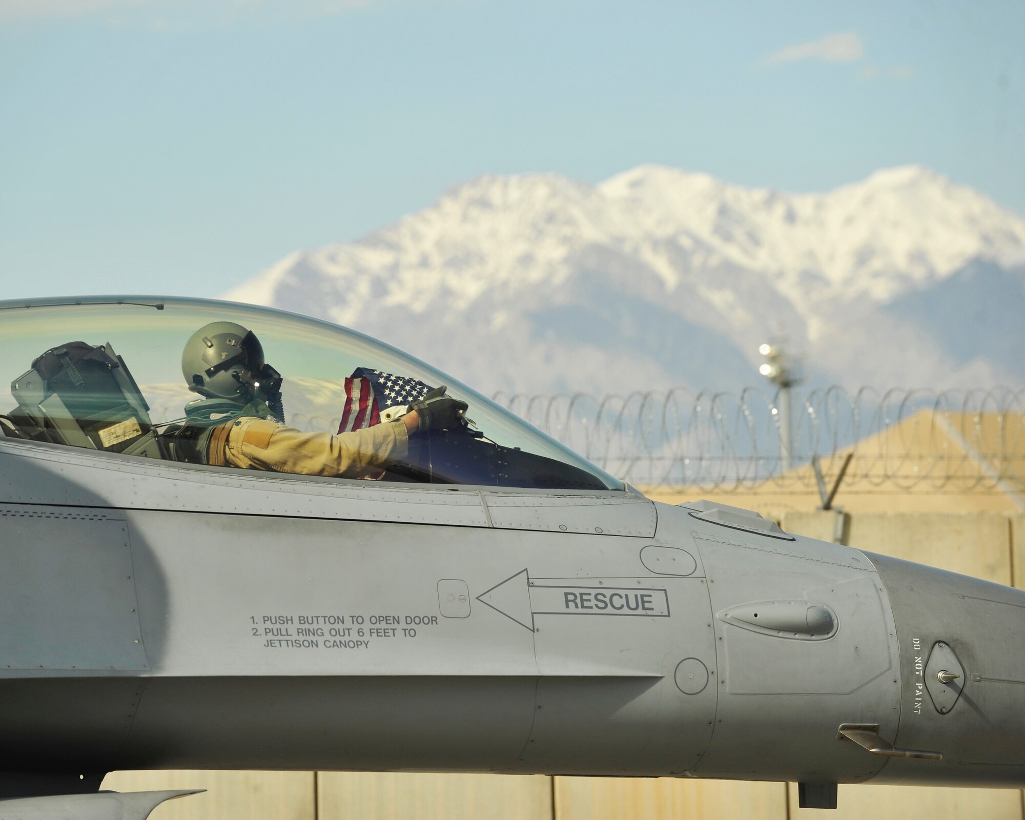 A F-16 fighter pilot assigned to the 457th Expeditionary Fighter Squadron unfolds an American flag shortly after arriving to Bagram Airfield, Afghanistan, 27 April, 2016. The 457th EFS is deployed to Afghanistan to support Operation Freedom’s Sentinel and the NATO Resolute Support mission. (U.S. Air Force photo by Capt. Korey Fratini/released)