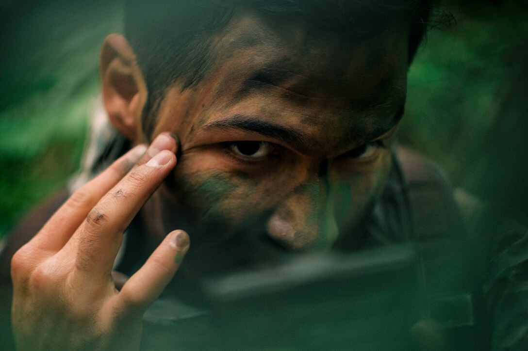 Capt. Daniel Stancin, a 36th Airlift Squadron navigator, applies face paint during survival, evasion, resistance and escape training at Tama Hills Recreation Area, Japan, April 21, 2016. The SERE training keeps personnel prepared for contingency situations, such as evading and escaping capture behind enemy lines. (U.S. Air Force photo/Senior Airman Delano Scott)