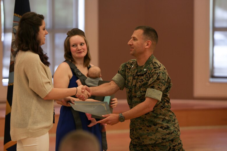 Lieutenant Col. Kenneth Lee, the commanding officer for 2nd Transportation Support Battalion, presents volunteer awards to Alex Renegar and Caitlyn Loomis, volunteers for 2nd Transportation Support Battalion and spouses of Marines in the battalion, during a ceremony held at Camp Lejeune, N. C., April 27, 2016. Lee said Renegar and Loomis always find time to give back to the unit, despite the workload and schedule of their Marine husbands within the battalion. (U.S. Marine Corps photo by Cpl. Melodie Snarr/Released)