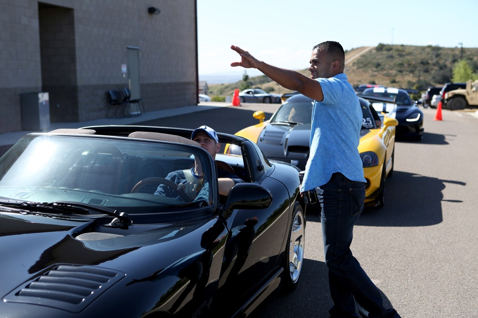 U.S. Marine Staff Sgt. Juan Lopez directs drivers during a family day celebration aboard Camp Pendleton, Calif., April 23, 2016. Lopez is the administration chief for 1st Explosive Ordnance Disposal Company, 7th Engineer Support Battalion, 1st Marine Logistics Group. Marines with 1st EOD Co. hosted the Viper Club of Southern California for the day as a part of their celebration, which included food, family activities, and a line-up of show cars. (U.S. Marine Corps photo by Cpl. Carson Gramley/released)