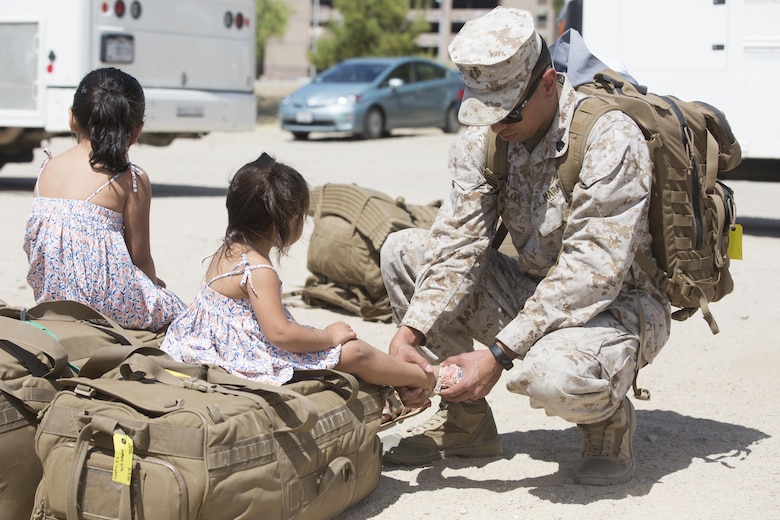 Sgt. Jonathan Lopez, rifleman, 1st Battalion, 7th Marine Regiment, adjusts his daughter’s sandal during the battalion’s homecoming at Del Valle Field April 23, 2016. 1/7 was deployed as part of Special Purpose Marine Air Ground Task Force-Crisis Response-Central Command 16.1. (Official Marine Corps photo by Cpl. Julio McGraw/Released)