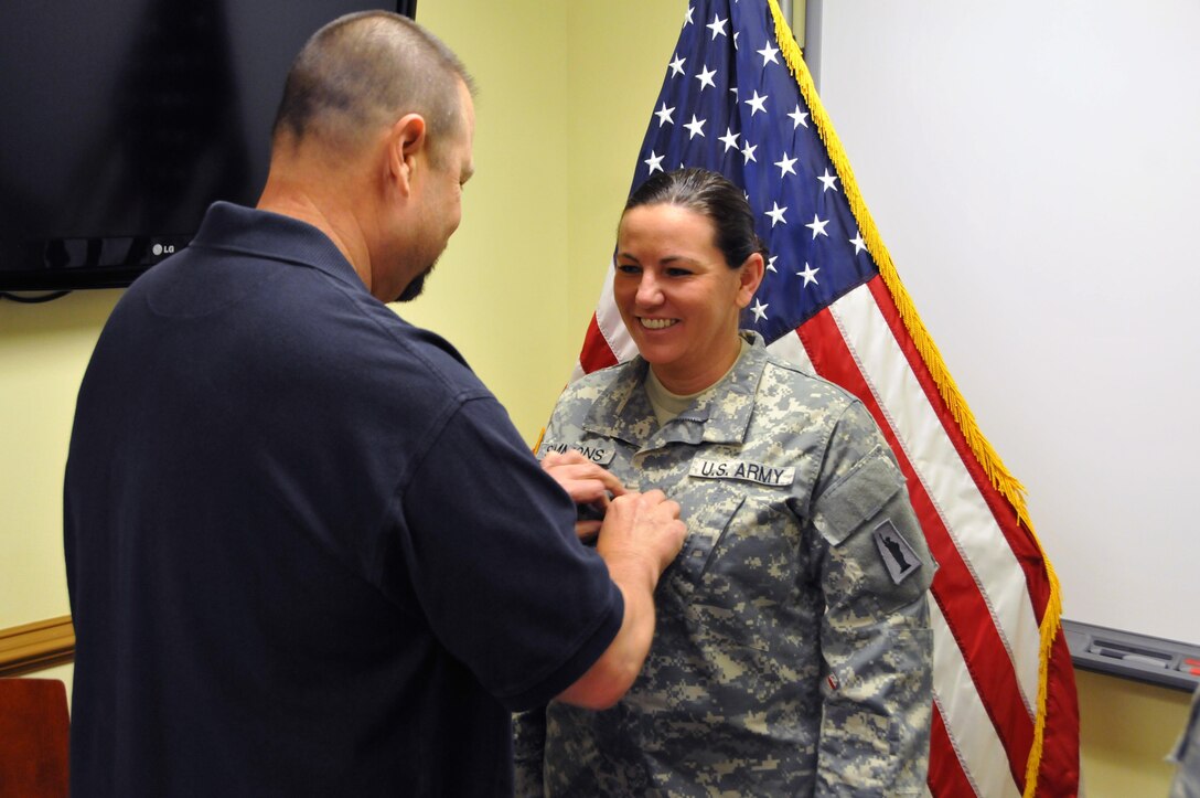 David Coles pins Staff Sgt. Heather Simmons, a native of Jacksonville, Florida assigned to the U.S. Army Reserve's 99th Regional Support Command at Joint Base McGuire Dix-Lakehurst, New Jersey, with the rank of Warrant Officer Candidate April 29.