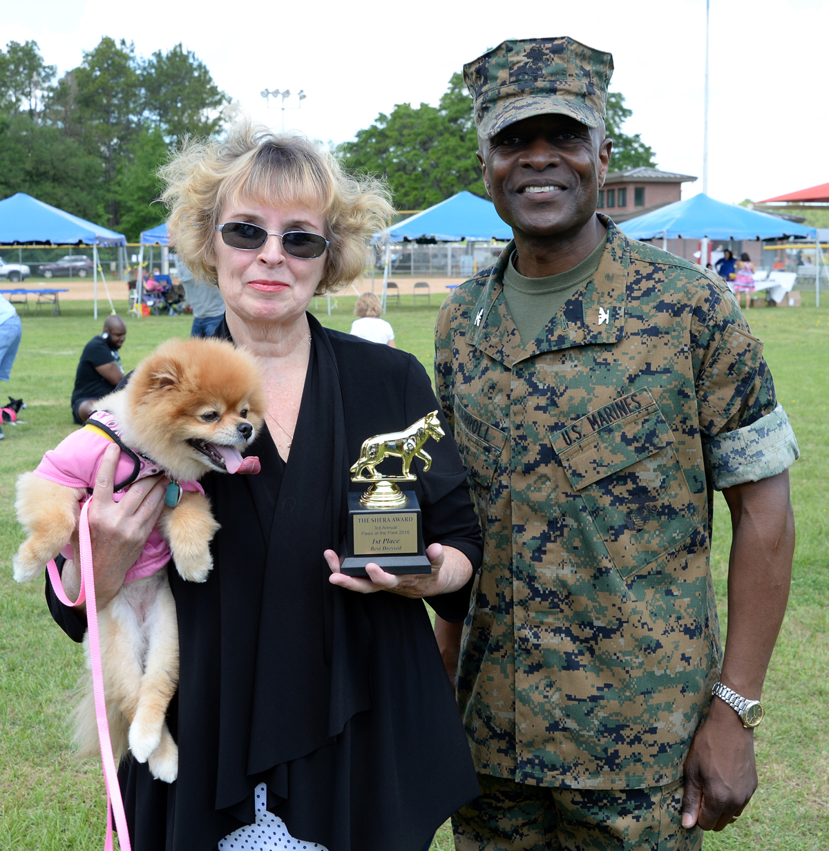 Chloe, a 7-year-old Pomeranian held by her owner Jane Fiore, defends her first place title in the Paws at the Park best dressed category at Marine Corps Logistics Base Albany’s Crouch Field, April 23. Chloe wore a pink T-shirt that read “Rainbows makes me smile.” Col. James C. Carroll III, commanding officer, MCLB Albany, presented the awards.