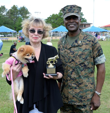 Chloe, a 7-year-old Pomeranian held by her owner Jane Fiore, defends her first place title in the Paws at the Park best dressed category at Marine Corps Logistics Base Albany’s Crouch Field, April 23. Chloe wore a pink T-shirt that read “Rainbows makes me smile.” Col. James C. Carroll III, commanding officer, MCLB Albany, presented the awards.