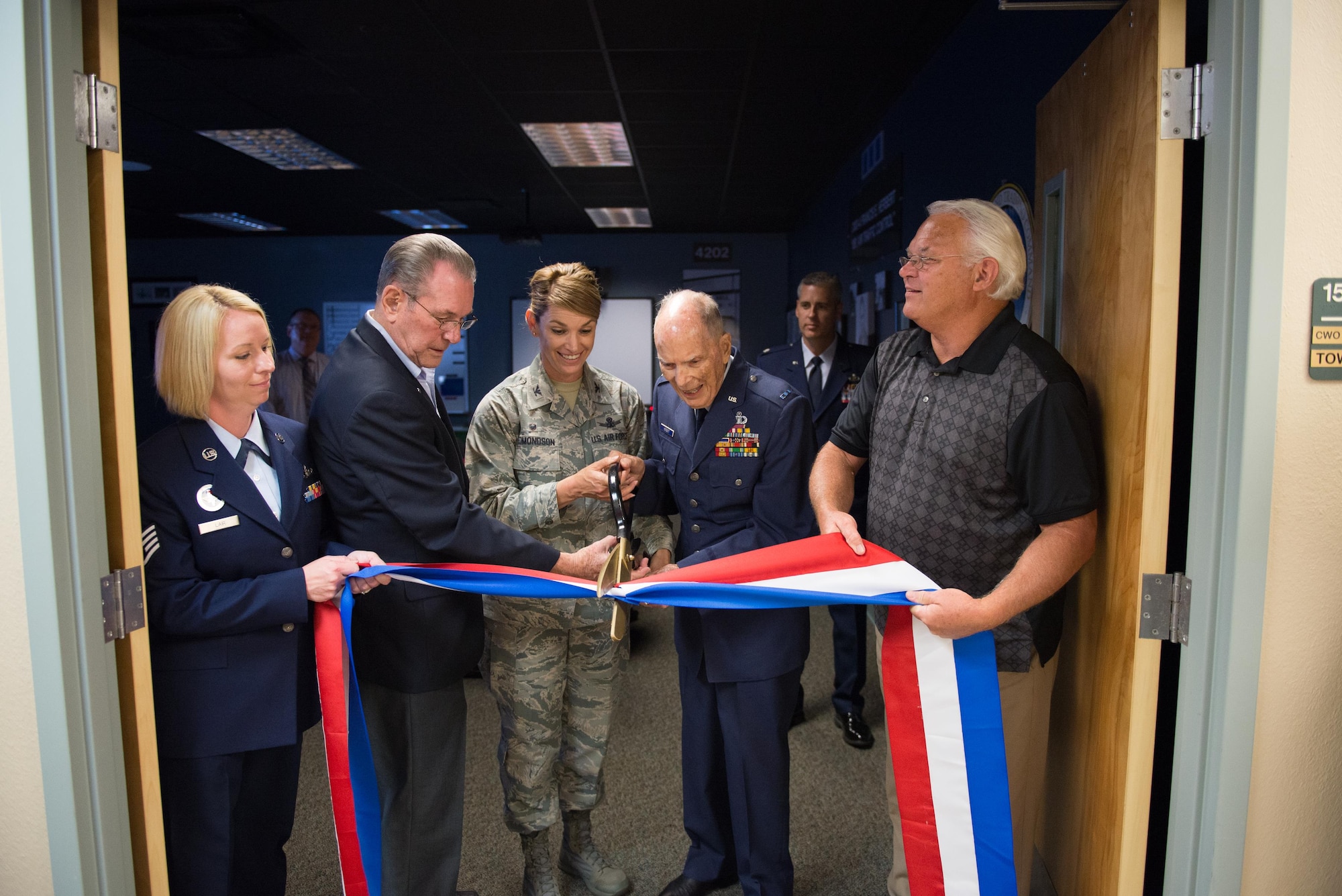 Retired Chief Master Sgt. J.J. Vollmuth; Col. Michele Edmondson, 81st Training Wing commander; and Retired Chief Warrant Officer 4 Francis Herbert cut a ribbon during a ceremony in Cody Hall April 26, 2016, Keesler Air Force Base, Miss. A room was dedicated to Herbert for his 50 years of service in air traffic control in the Army, Army Air Corps, and Air Force from 1942-1972, then as a Keesler civilian instructor for 20 years. (U.S. Air Force photo by Marie Floyd)