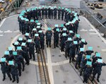 Sailors on board the Ticonderoga-class guided-missile cruiser USS Chancellorsville (CG 62) gather on the flight deck to form a teal ribbon, in recognition of  Sexual Assault Prevention (SAPR) Month. The teal ribbon signifies the U.S. Navy’s zero tolerance policy against sexual assault. 