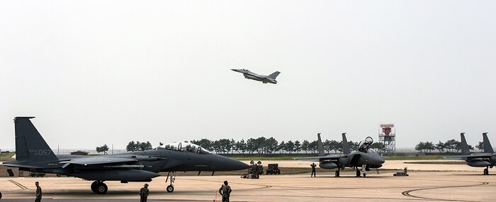 Republic of Korea air force F-15Ks from the 11th Fighter Wing, Daegu Air Base, ROK, prepare for flight as a KF-16 from the 20th Fighter Wing, Seosan Air Base, ROK takes off on the runway during Max Thunder 16 at Kunsan Air Base, Republic of Korea, April 18, 2016. Exercise Max Thunder is part of a continuous exercise program to enhance interoperability between U.S. and ROK forces. 