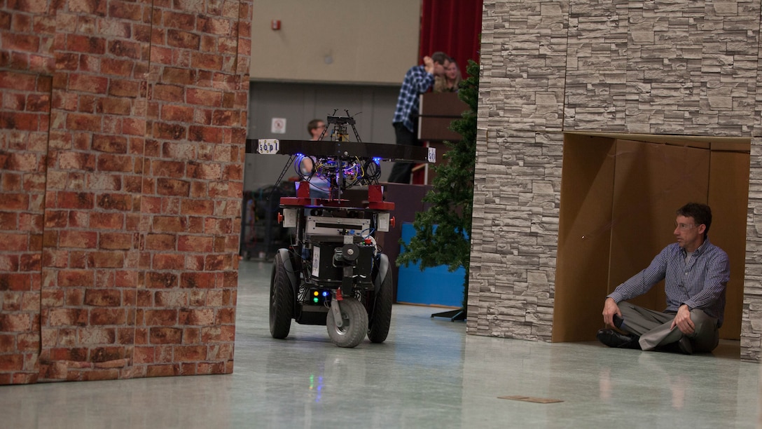 The Unmanned Tactical Autonomous Control and Collaboration searches for a simulated enemy combatant in a mock town inside Ellis Hall at Marine Corps Base Quantico, April 19, 2016. The UTACC is a team of aerial and ground robots using the Distributed Real-time Autonomously Guided Operations Engine to provide multi-dimensional intelligence, surveillance and reconnaissance to the squad-level units. 