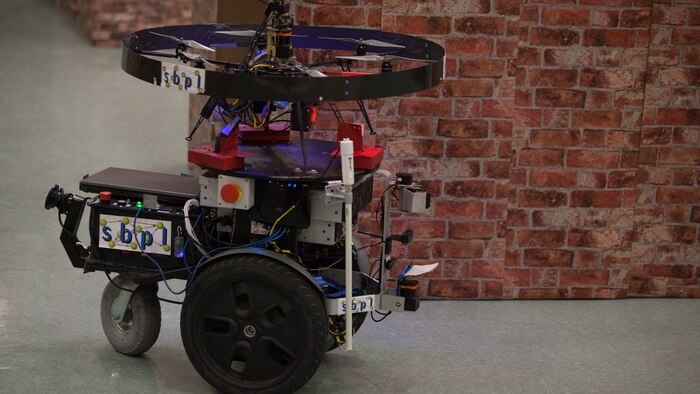 The Unmanned Tactical Autonomous Control and Collaboration patrols a simulated town indoors in Ellis Hall at Marine Corps Base Quantico, April 19, 2016. The UTACC is a team of aerial and ground robots using the Distributed Real-time Autonomously Guided Operations Engine to provide multi-dimensional intelligence, surveillance and reconnaissance to the squad-level units. Though the tests are conceptual, the UTACC represents potential capabilities for robotics integrated into squad-level units