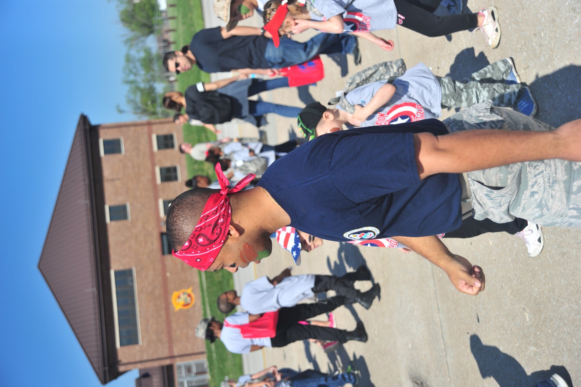 Children, along with their respective chalk leader, Jermaine Walton, a prime base engineer emergency force apprentice, march onto the flightline during Operation Spirit at Whiteman Air Force Base, Mo., April 23, 2016. The children were divided into seven groups to learn about various aspects of the deployment process to include combative training, survival tactics and communications operations. (U.S. Air Force photo by Senior Airman Jovan Banks)