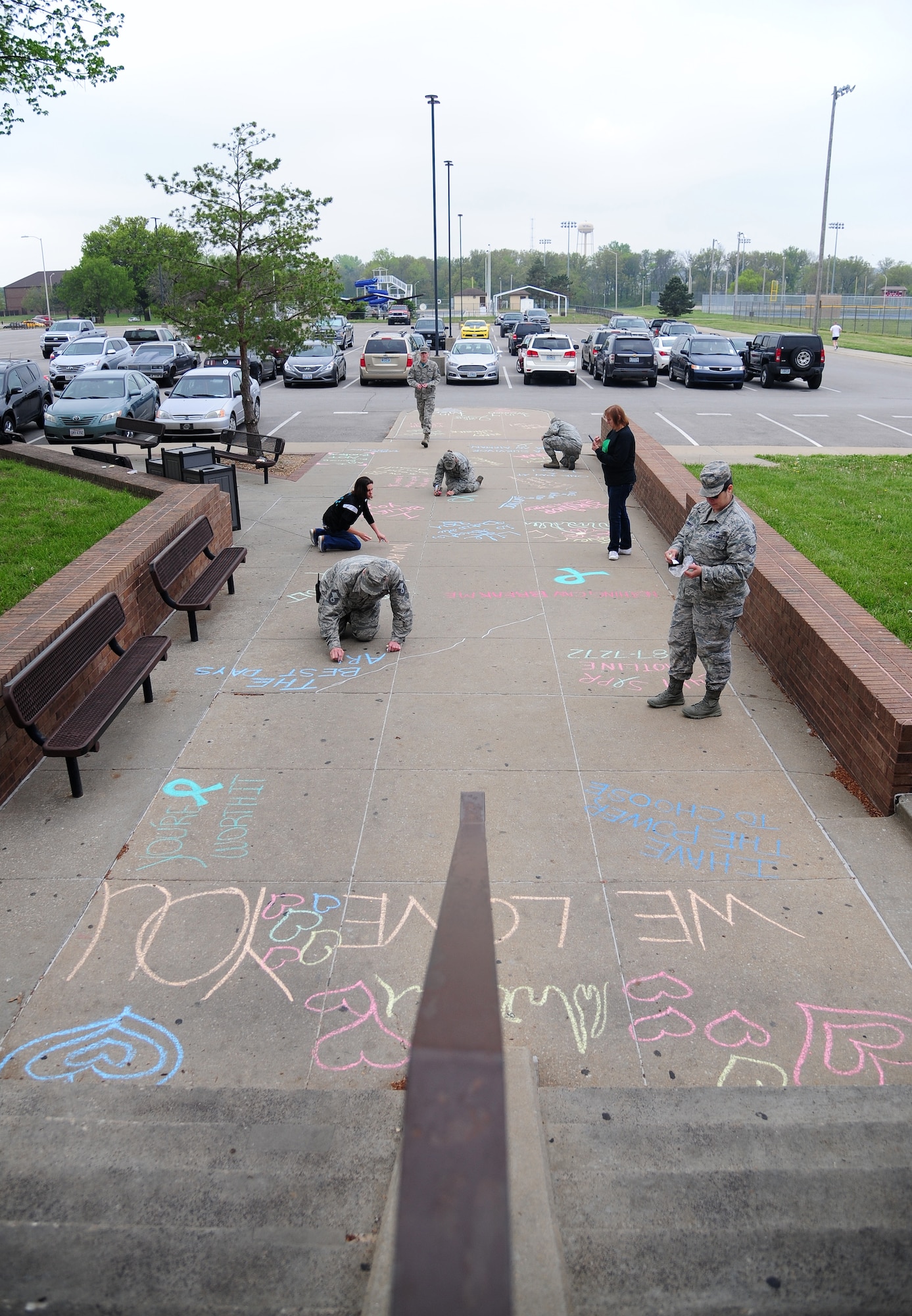 Sexual Assault Prevention and Response team victim’s advocates use chalk to write inspirational messages in front of the fitness center at Whiteman Air Force Base, Mo., April 22, 2016. The messages were written to support survivors of sexual assault in recognition of Sexual Assault Awareness Month. (U.S. Air Force photo by Senior Airman Joel Pfiester)