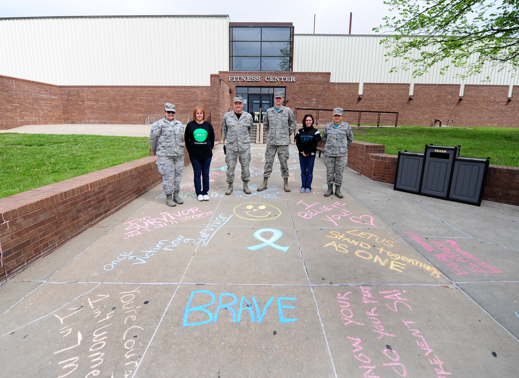 Sexual Assault Prevention and Response team victim’s advocates pose in front of inspiring messages written in chalk at Whiteman Air Force Base, Mo., April 22, 2016. The messages were written in solidarity for survivors of sexual assault. (U.S. Air Force photo by Senior Airman Joel Pfiester)